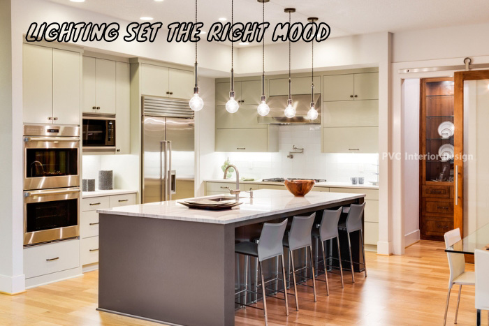 Chic and well-lit kitchen space designed by Janani PVC Interior Design in Bengaluru, highlighting mood-setting pendant lights over a modern kitchen island, perfect for lively family gatherings